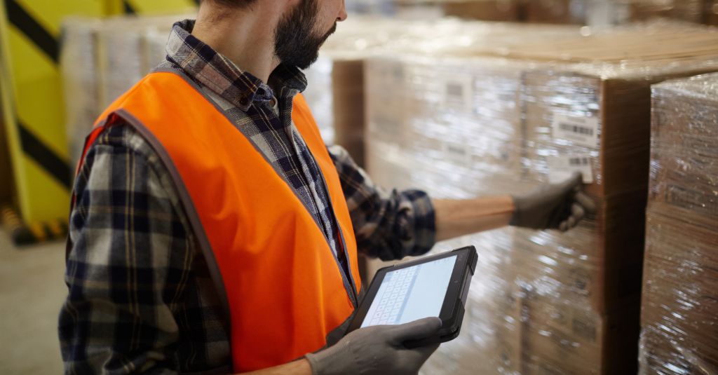 Copy of Blog Cover - 1 warehouse worker inspecting items while holding a Getac rugged tablet
