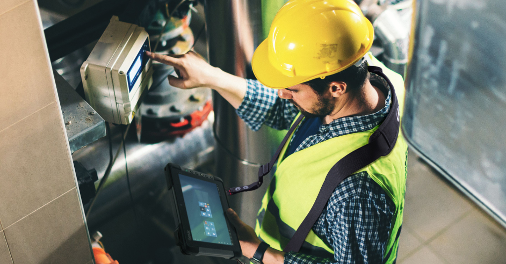 Utility worker checking meter while holding a Getac rugged tablet.