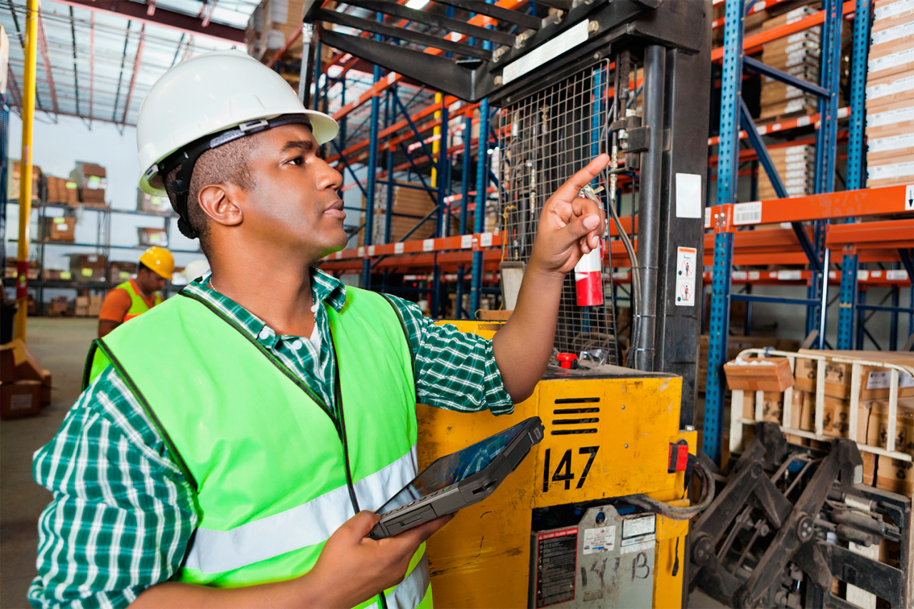 Warehouse worker inspecting stocks while holding a Getac rugged tablet.