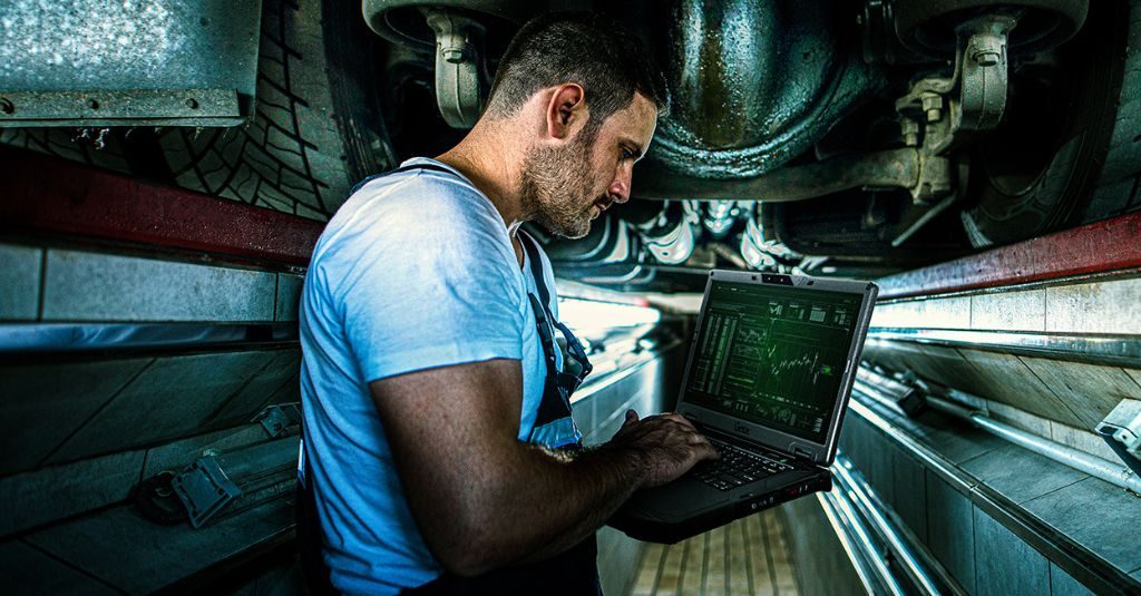 automotive technician working with rugged laptop at the workshop